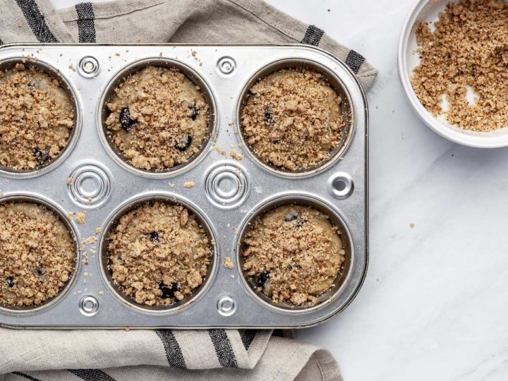 Overhead view of unbaked blueberry muffins in a muffin tin.