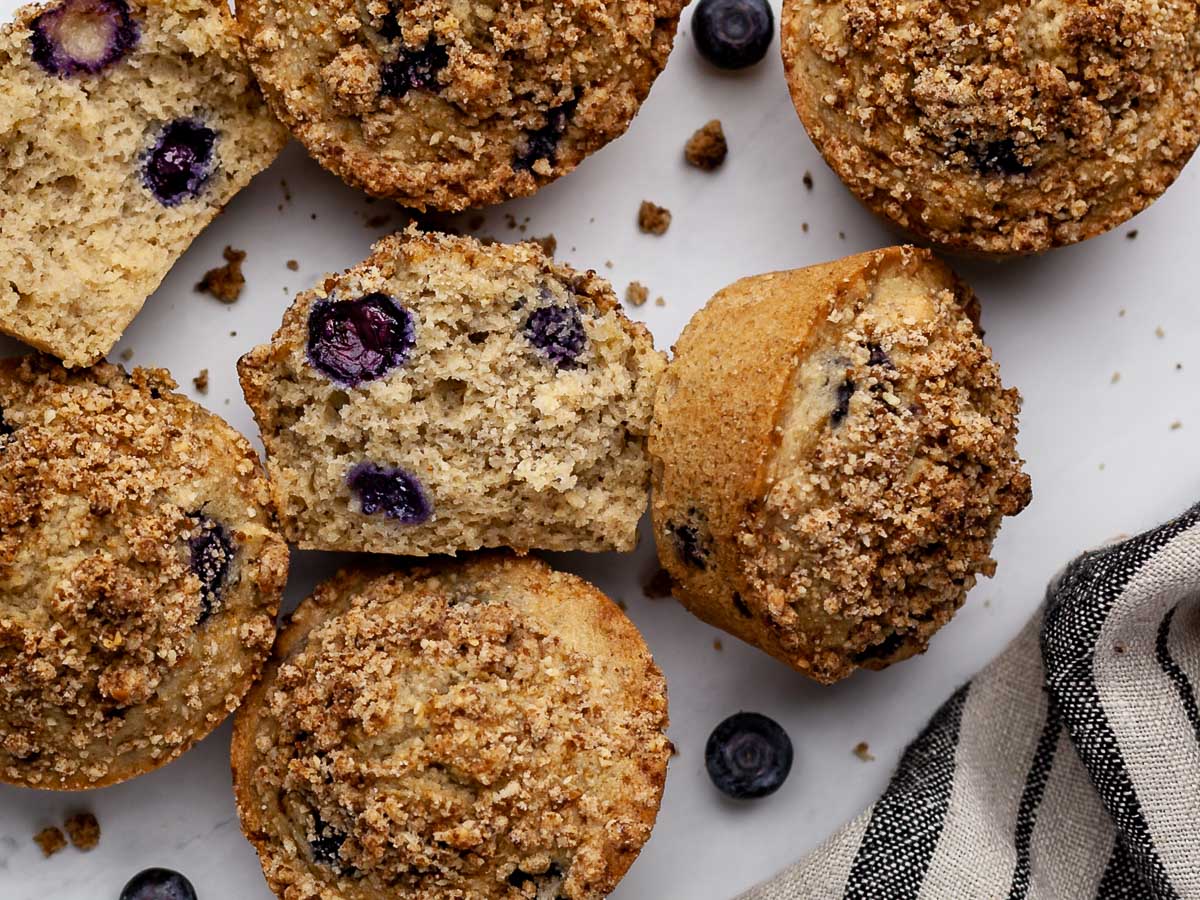 Inside view of a vegan low-fodmap blueberry muffin with whole muffins surrounding.