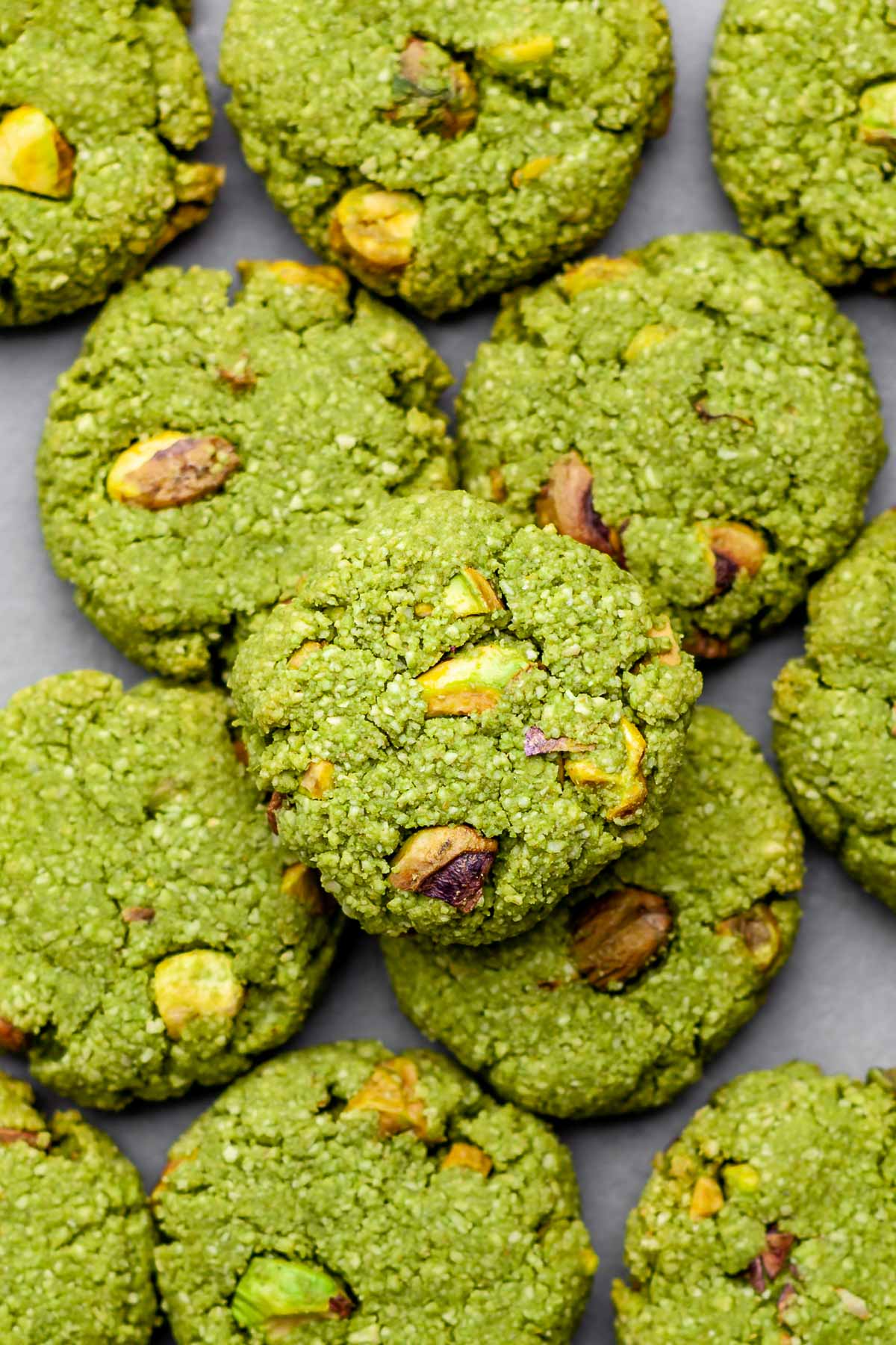Overhead view of a pile of vegan matcha cookies on a concrete background.