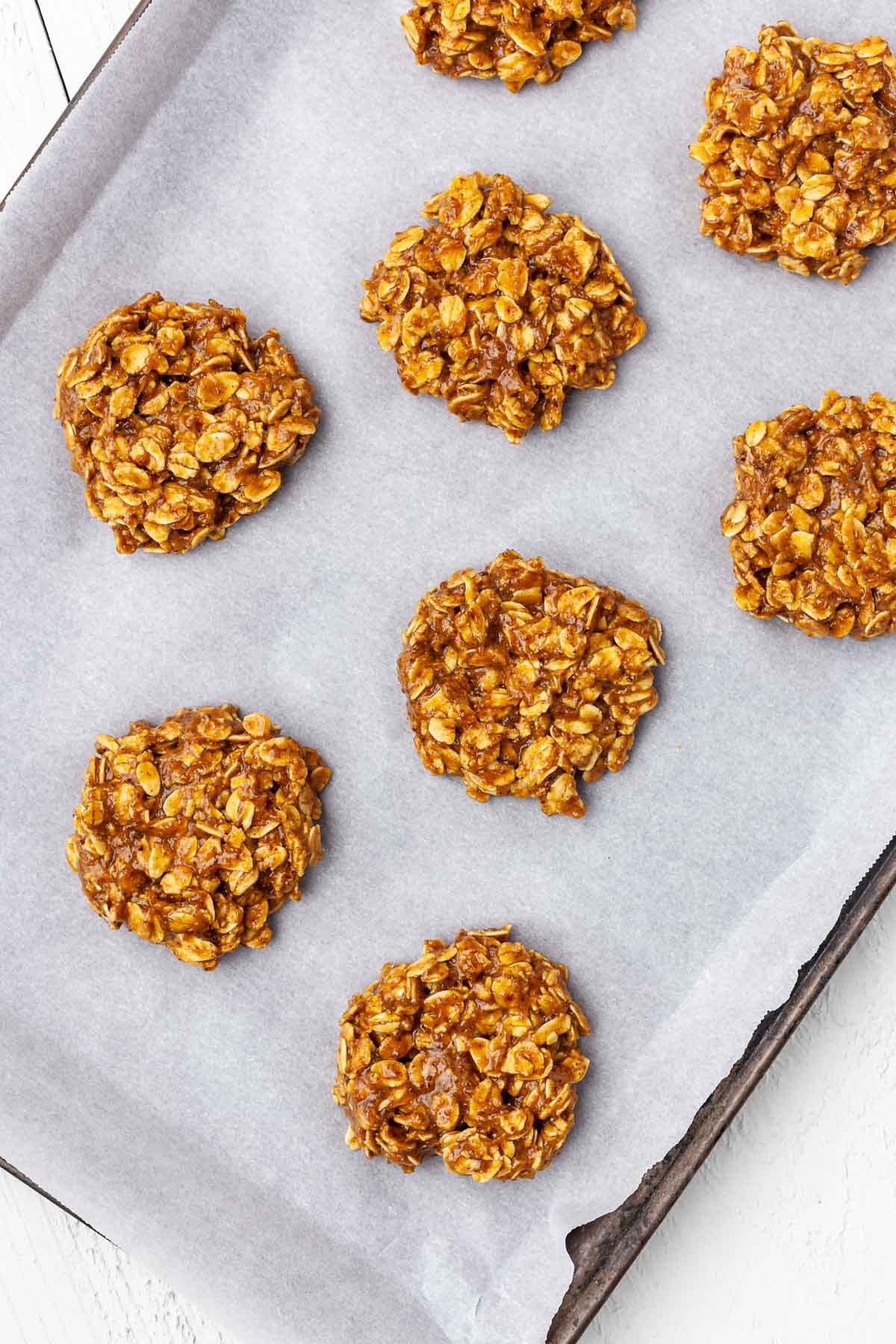 Overhead view of unbaked vegan peanut butter oatmeal cookies on a baking sheet.