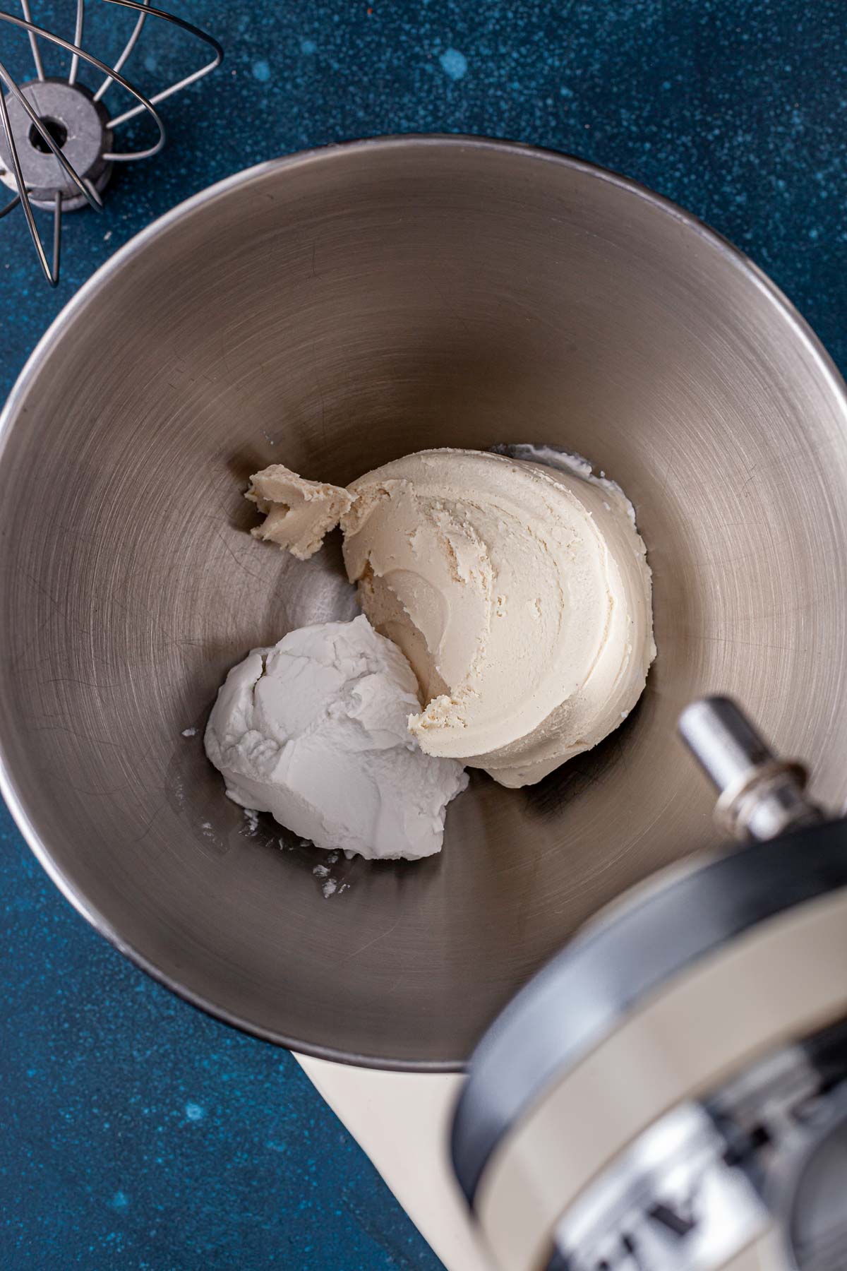 Coconut cream and vegan cream cheese in the bowl of a stand mixer.